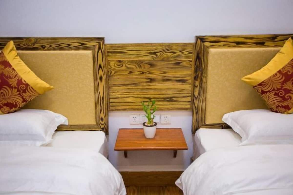 A hotel room with two beds, each with a wooden headboard and a small bedside table with a plant.