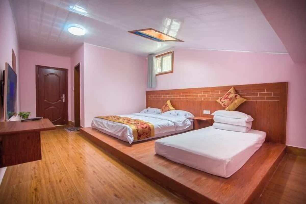 A bedroom with two beds, a wooden desk, a TV, and a window.