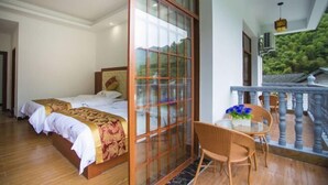 A room with a bed, a glass partition, a balcony with a railing, and a table with chairs. - Haolaiju Inn (Zhangjiajie)