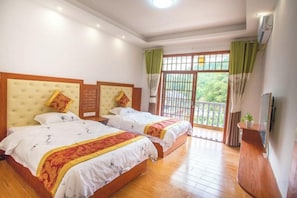 A hotel room with two beds, a balcony, and a view of greenery. - Haolaiju Inn (Zhangjiajie)