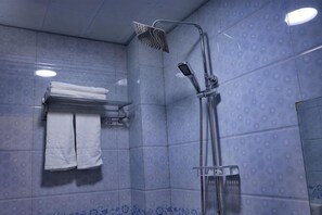 Un bagno con doccia, un portascopevoli con asciugamani e una parete con piastrelle decorate.