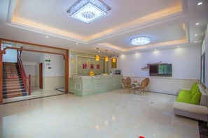 A hotel lobby with a reception desk, seating area, and a staircase. - Haolaiju Inn (Zhangjiajie)