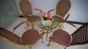 A round glass table with four wicker chairs, each with a curved backrest. A bouquet of pink and white flowers is placed on the table. - Haolaiju Inn (Zhangjiajie)