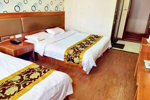 Habitación de hotel con dos camas, cabeceros de madera, mesitas de noche con teléfono y un corredor de cama estampado.