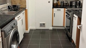 A compact kitchen with a washing machine, stove, microwave, and cabinets. - Views from the 8th (London)