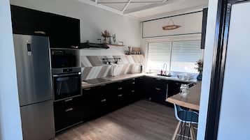 Een moderne keuken met een inbouwoven, magnetron en een roestvrijstalen koelkast.