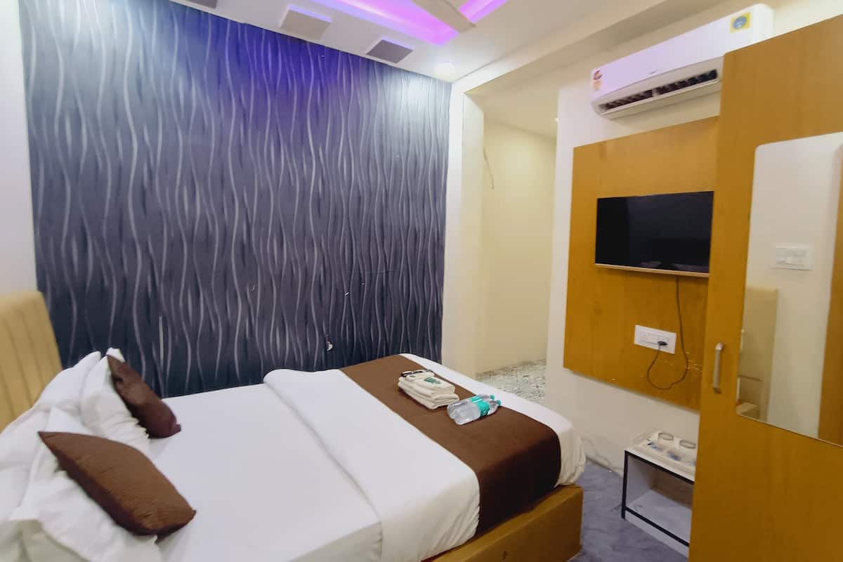 Una habitación de hotel con cama, televisión, aire acondicionado y armario.