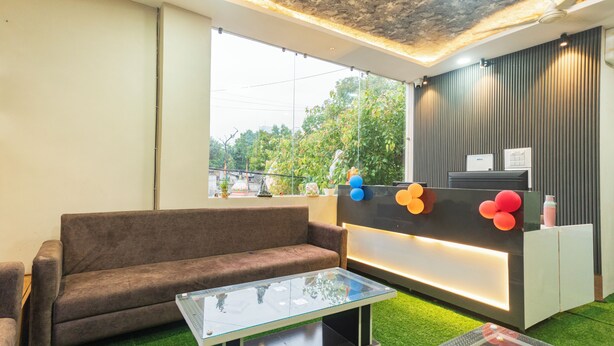 Un área de recepción moderna con un sofá, una mesa de vidrio y un mostrador de recepción con globos.