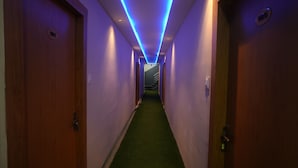 Un pasillo con puertas de madera, alfombra verde e iluminación azul.