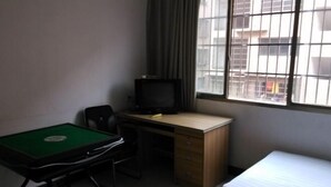 Ein Zimmer mit einem grünen Billardtisch, einem Holztisch, einem Fernseher, einem Stuhl und einem Bett.