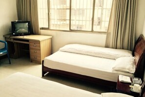 Una habitación con una cama, un escritorio con computadora y una ventana con cortinas.