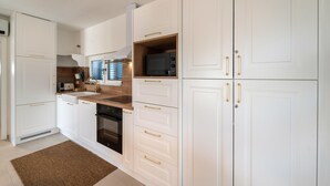 Une cuisine moderne avec des meubles blancs, un plan de travail en bois et des appareils électroménagers en acier inoxydable.