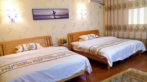 Ein Hotelzimmer mit zwei Holzbett, einem kleinen Tisch und einer Wandklimaanlage.