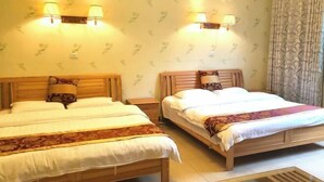 Ein Doppelzimmer mit zwei Betten, jeweils mit hölzernen Rahmen und weißer Bettwäsche. An den Wänden sind Lampen angebracht und die Tapete ist gemustert.
