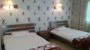 Ein Hotelzimmer mit zwei Betten, einem Nachttisch und Wandlampen.