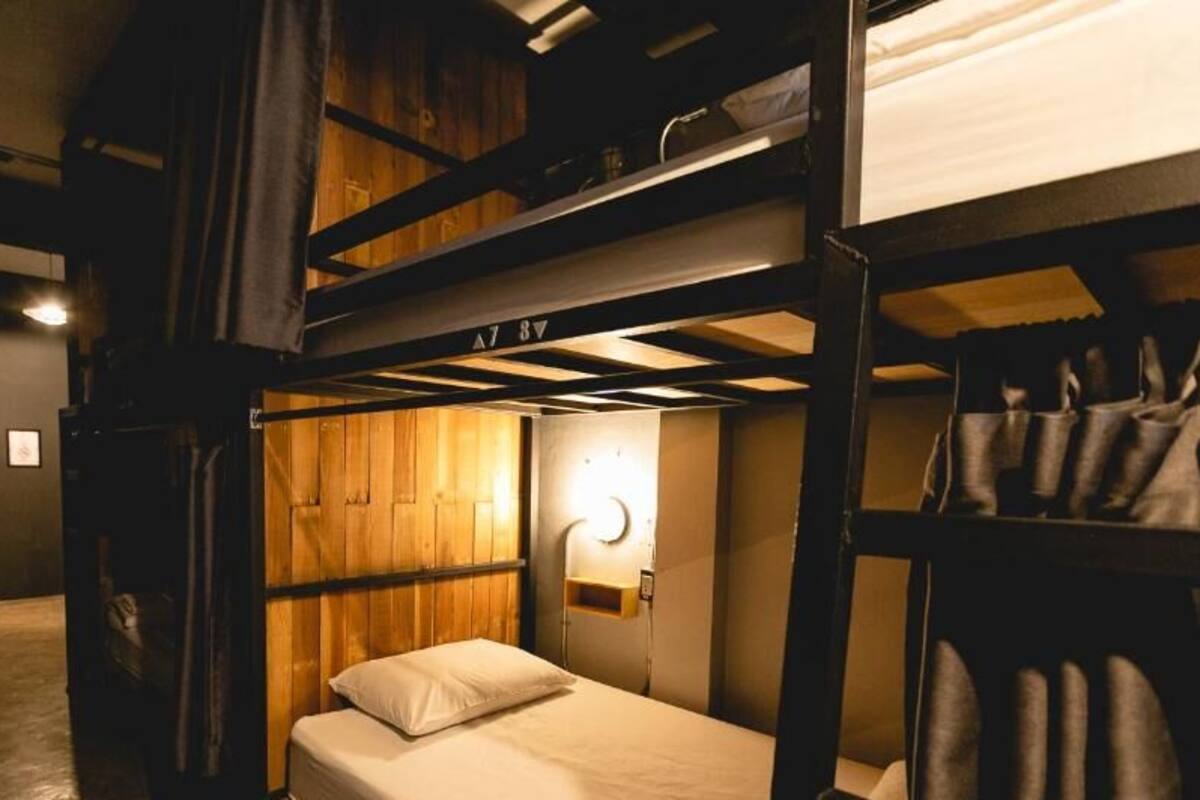 A bunk bed room with a wooden wall and a bedside lamp.