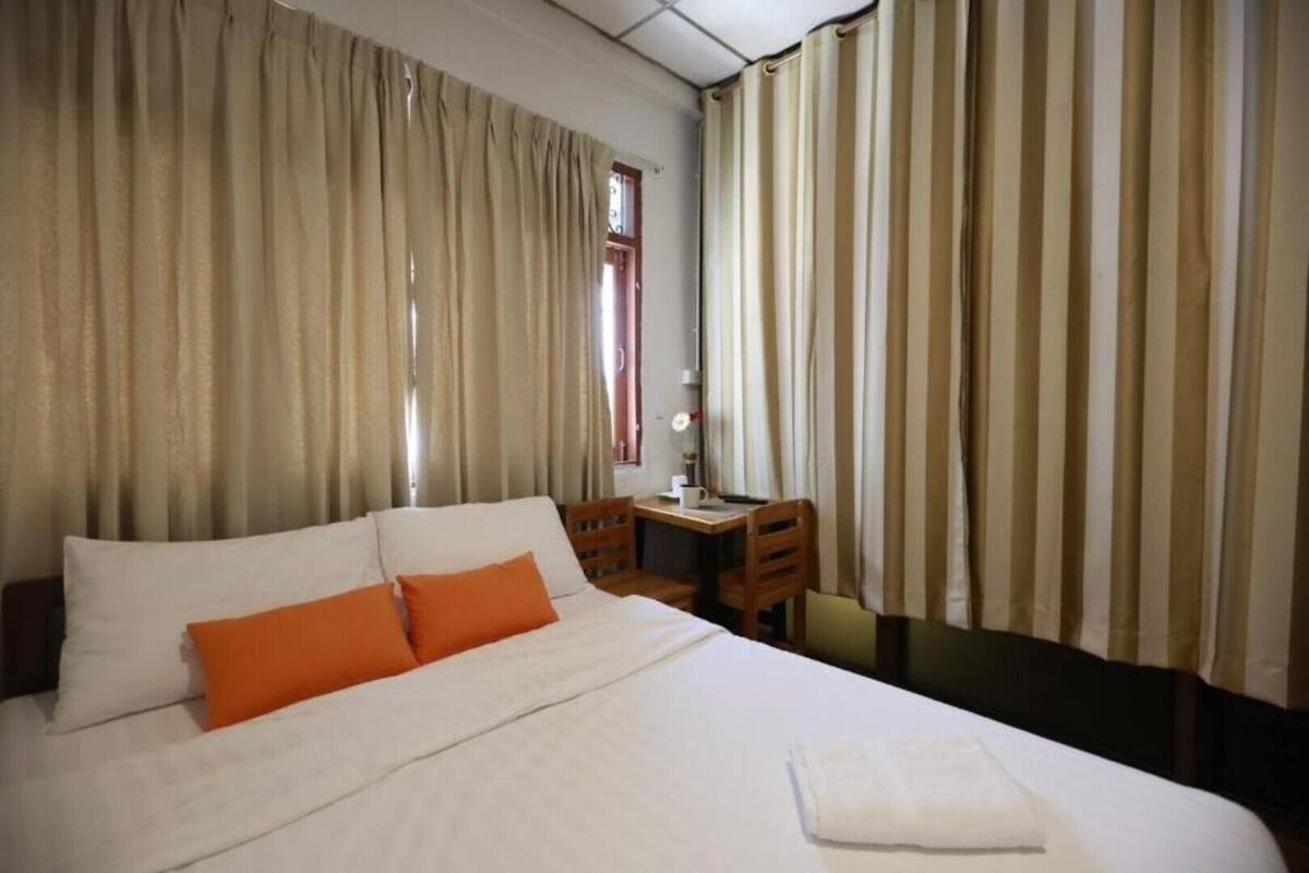 A hotel room with a large bed, a desk, and curtains.