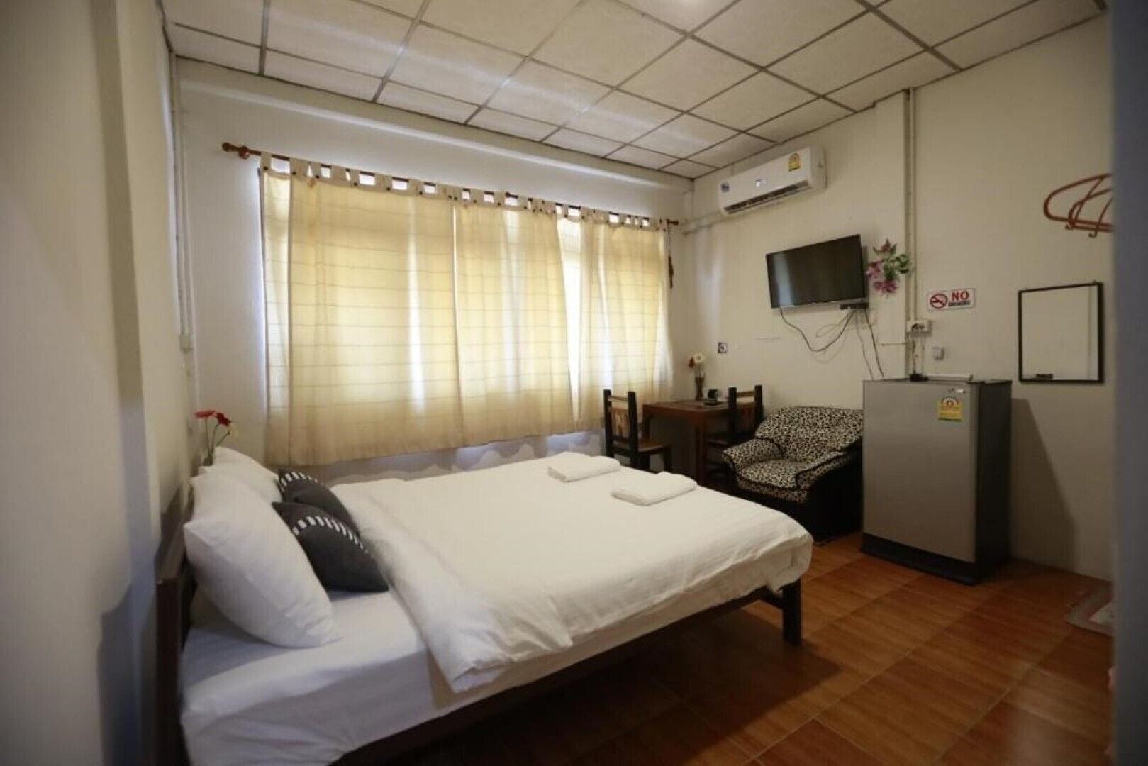 A bedroom with a bed, a desk, a chair, and a television.