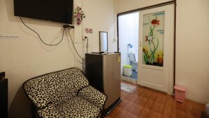 A room with a leopard-print sofa, a TV mounted on the wall, a no-smoking sign, and a door with a floral painting. - Banana Hostel Donmuang (Bangkok)