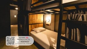 A bunk bed room with a wooden headboard, a bedside table with a lamp, and a suitcase on the floor. - Banana Hostel Donmuang (Bangkok)