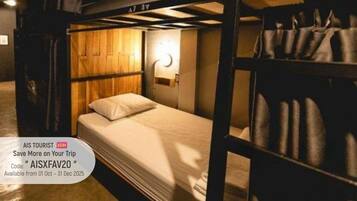 A bunk bed room with a wooden headboard, a bedside table with a lamp, and a suitcase on the floor.