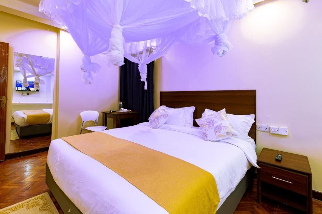 Une chambre d’hôtel avec un grand lit, une table de chevet, une petite table et une chaise.