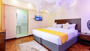A hotel room with a bed, bedside table, and a television on the wall. - Markson Hotel Kilimani (Nairobi)