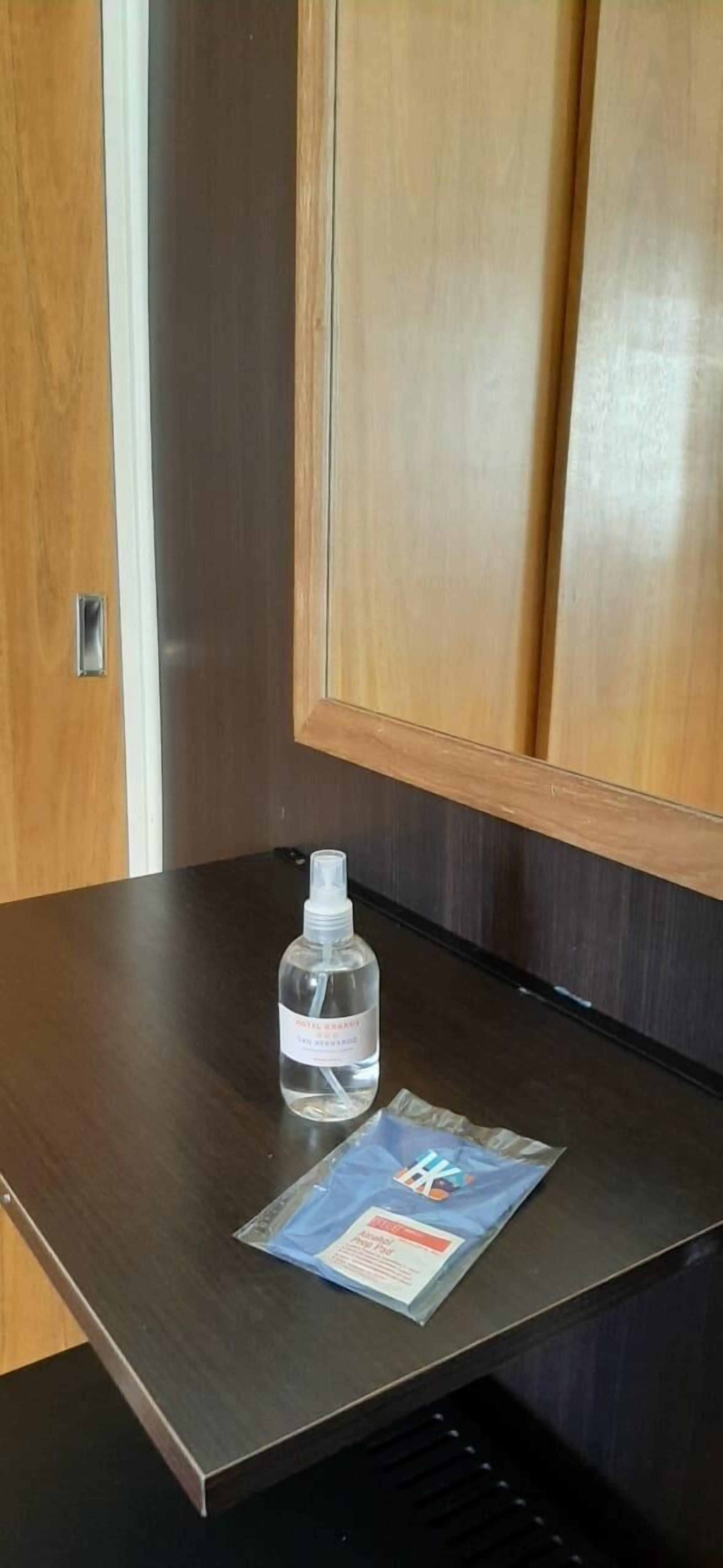 Une table en bois, sur laquelle se trouvent une bouteille de gel hydroalcoolique et un paquet de mouchoirs.