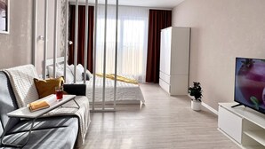 Una habitación de hotel moderna con una cama, un sofá, un televisor y una planta en maceta.