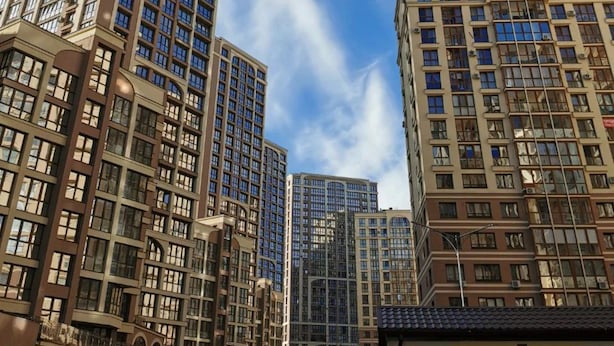 Un edificio de gran altura con varios pisos y ventanas amplias, rodeado de otros edificios altos.