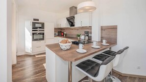 Uma cozinha moderna com ilha central, banquetas e forno embutido.