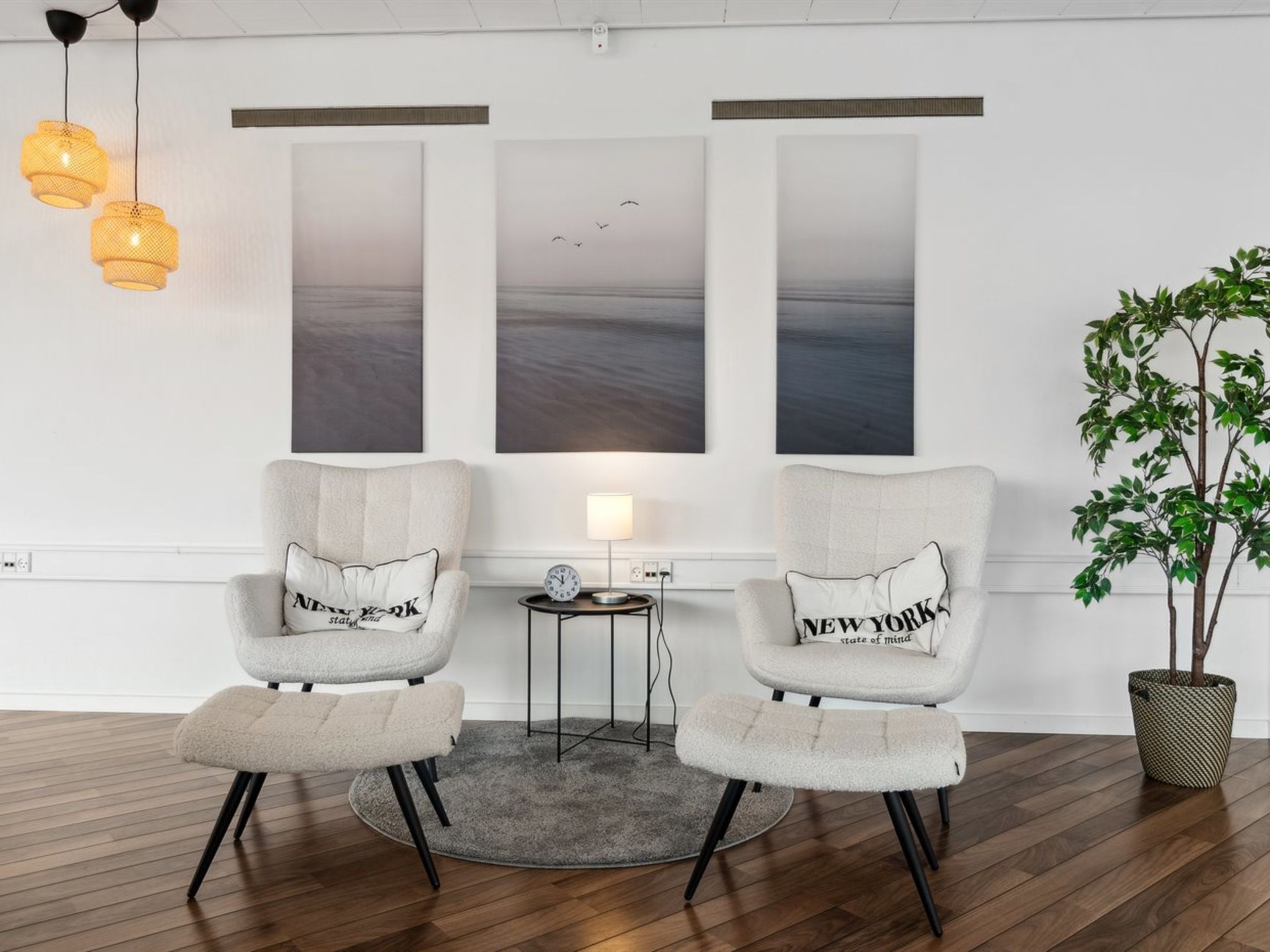 Una habitación moderna con dos sillones, una mesita de noche con una lámpara y una planta en maceta.