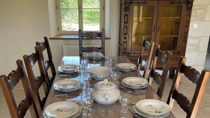 Une table à manger dressée avec des assiettes, des verres et des couverts, entourée de chaises en bois.