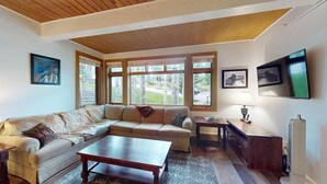 A living room with a sectional sofa, a coffee table, and a TV mounted on the wall.