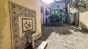 A narrow alleyway with a tiled wall featuring geometric patterns and a stone basin.