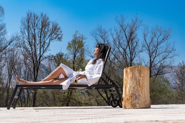 A person relaxing on a chair outdoors with trees in the background.