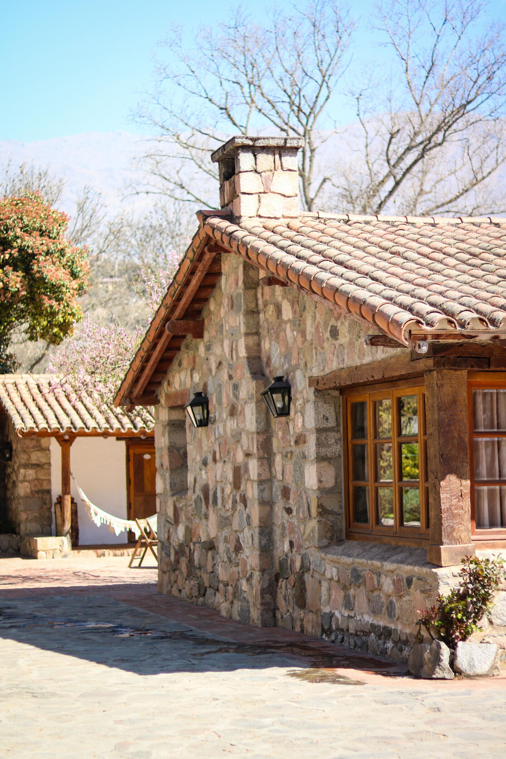 A stone building with a tiled roof, a wooden door, and a window.