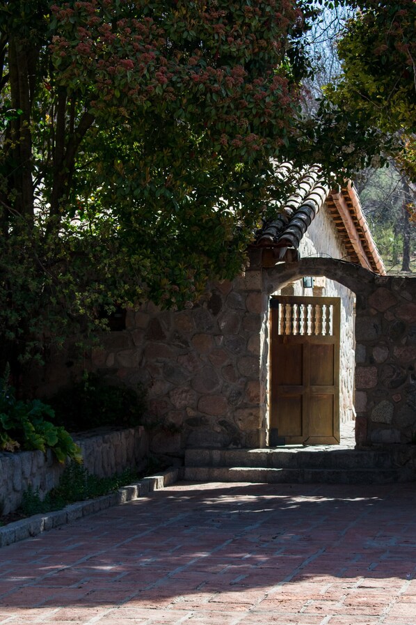 A stone archway leading to a building with a tiled roof.