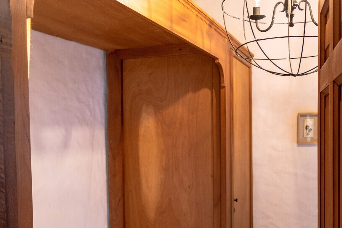 A single bed in a room with wooden walls and a door.