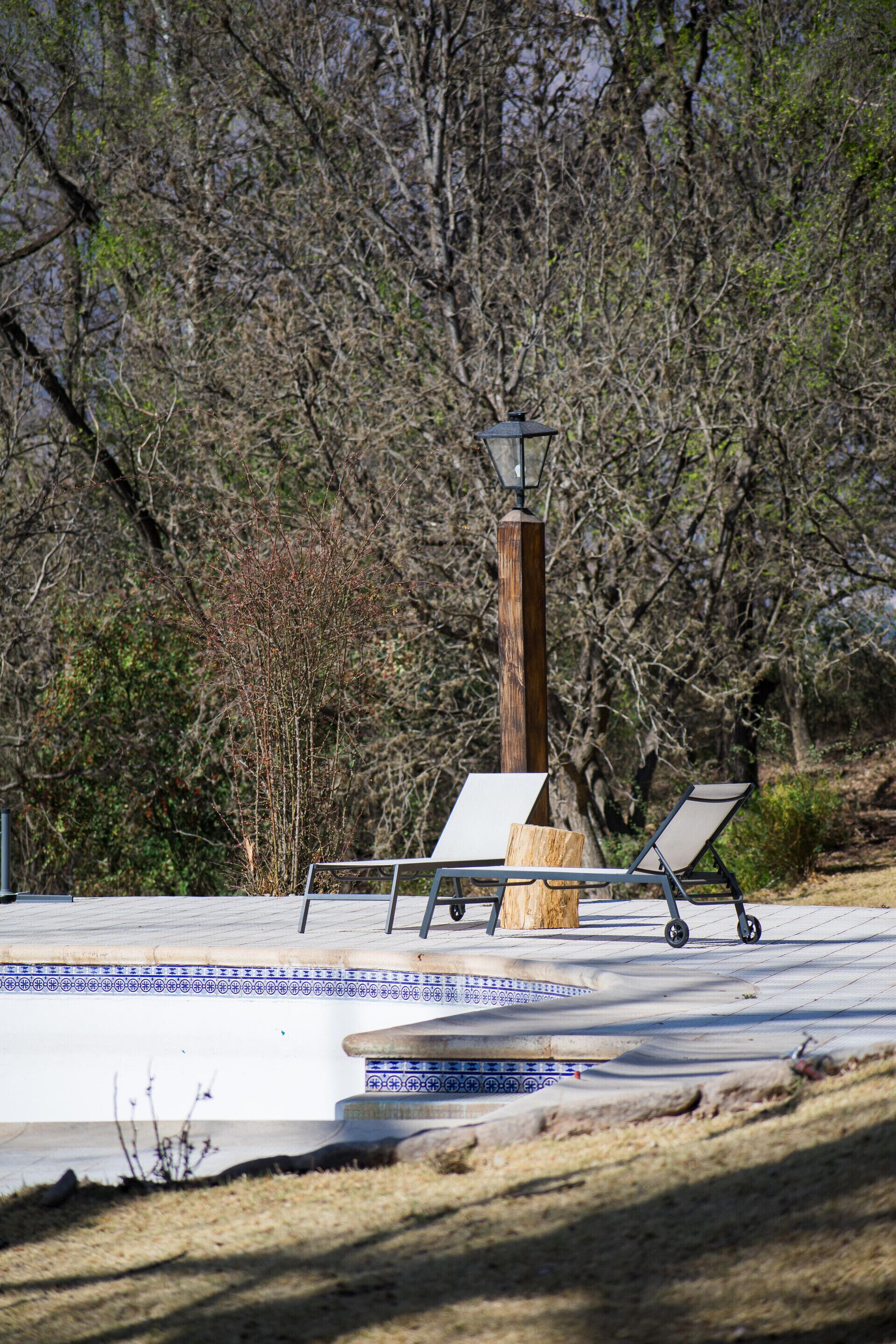 A pool area with two lounge chairs and a lamp post.