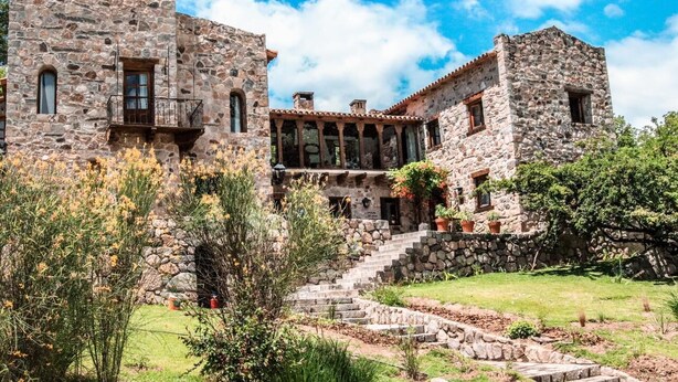 A stone building with a courtyard, featuring a staircase leading to a balcony.