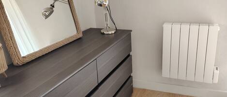 A room with a dark wooden dresser, a mirror, and a desk lamp.