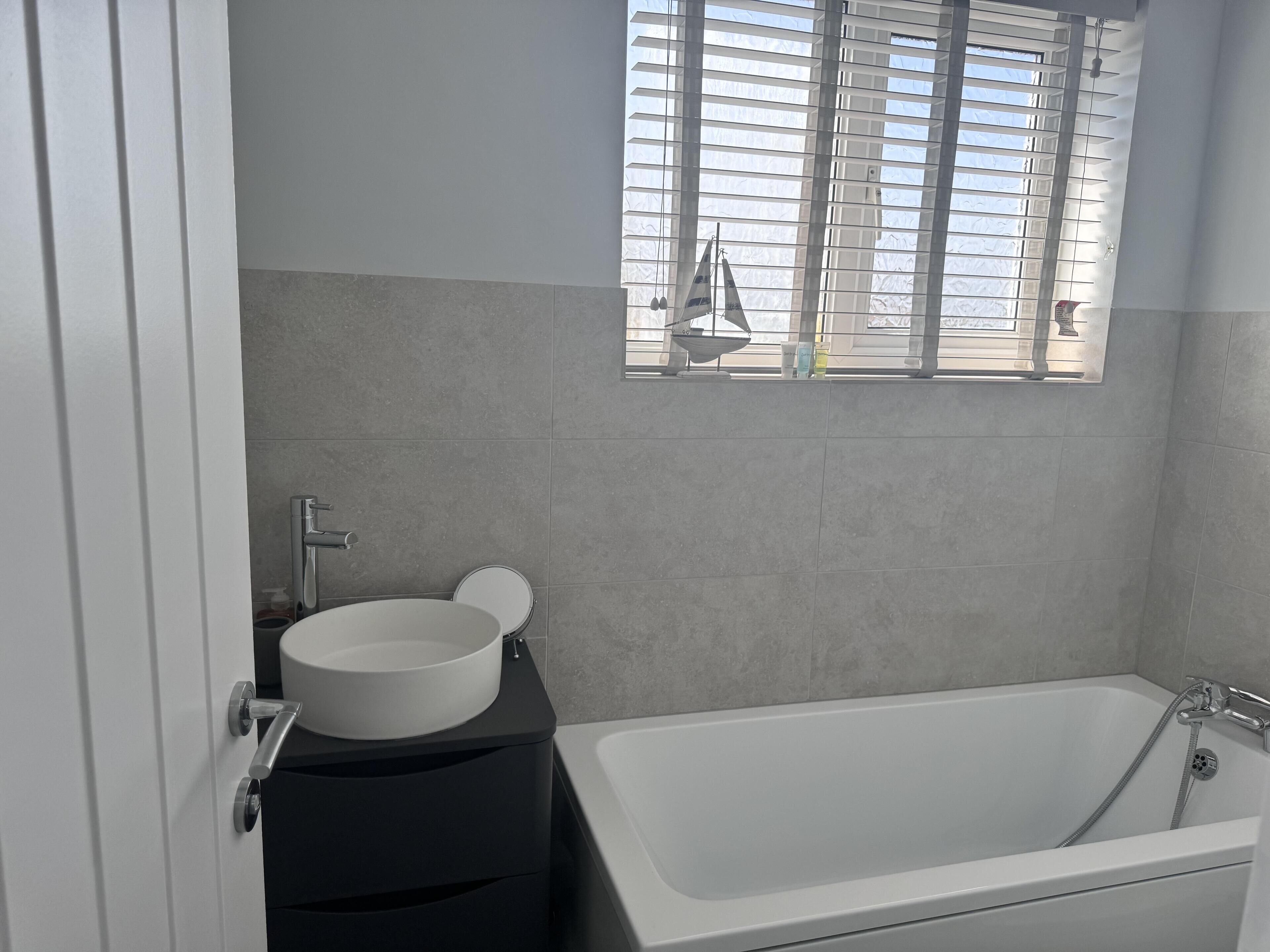 A bathroom with a bathtub, a round mirror, and a white sink.