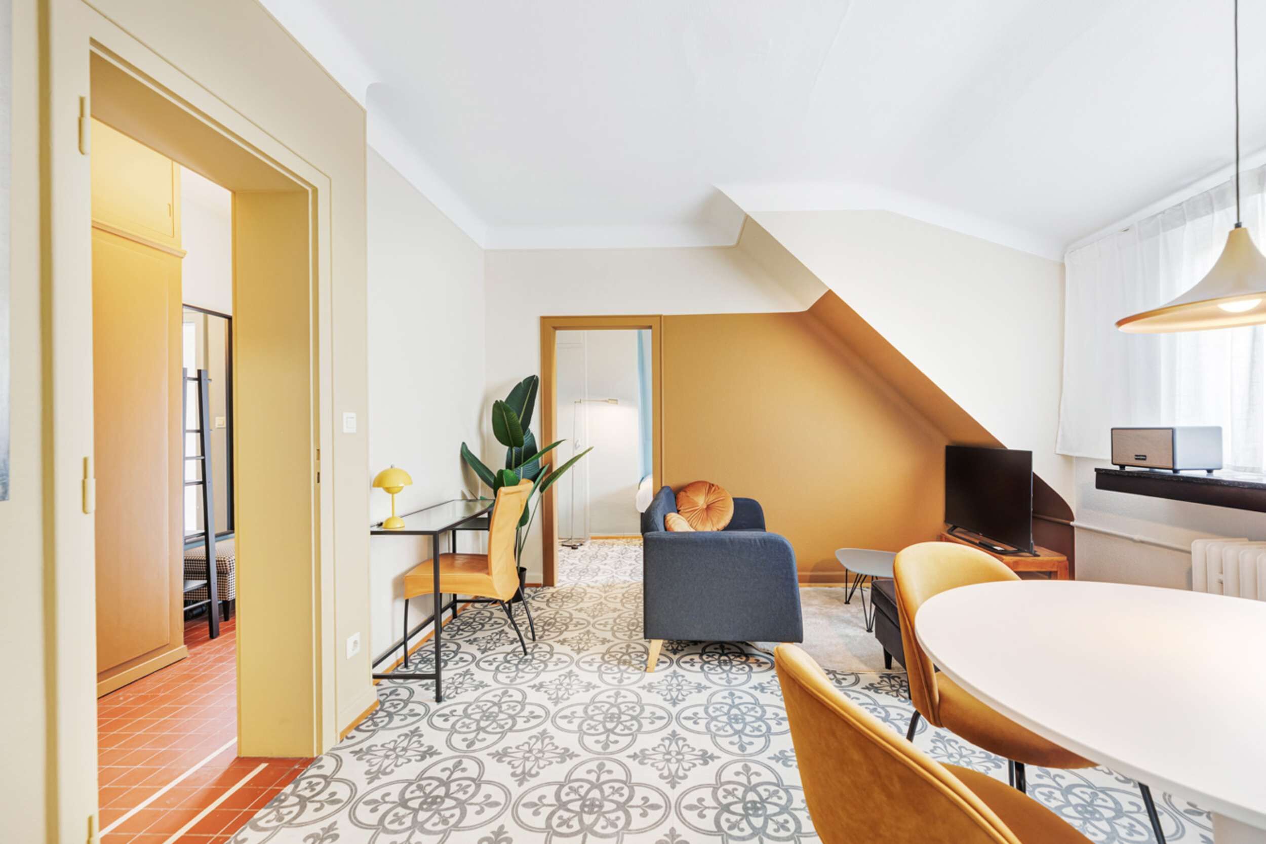 Una habitación de hotel moderna con comedor, sofá, televisión y escalera.
