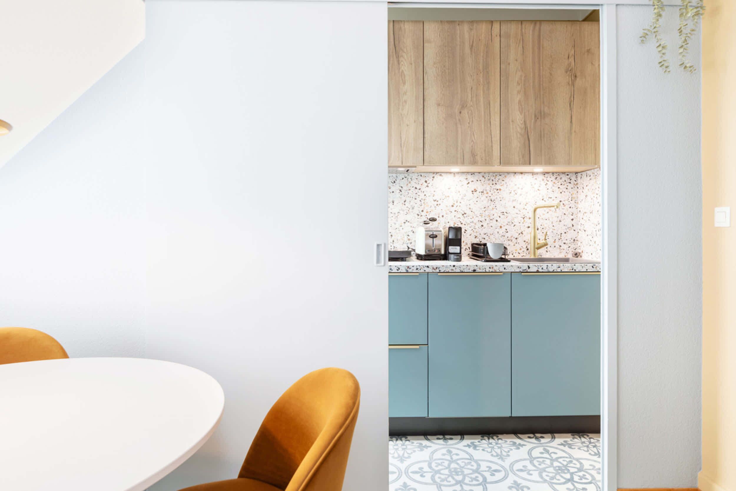 Een moderne keuken met lichtblauwe kastjes, een witte aanrecht en een decoratieve spatwand.