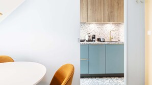 Une cuisine moderne avec des meubles bleu clair, un plan de travail blanc et un pare-feu décoratif.