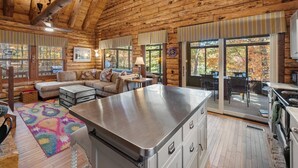 A log cabin interior with a kitchen, dining area, and living room. - Log Cabin w/ Hot Tub & Waterfront Patio! (Harpers Ferry)