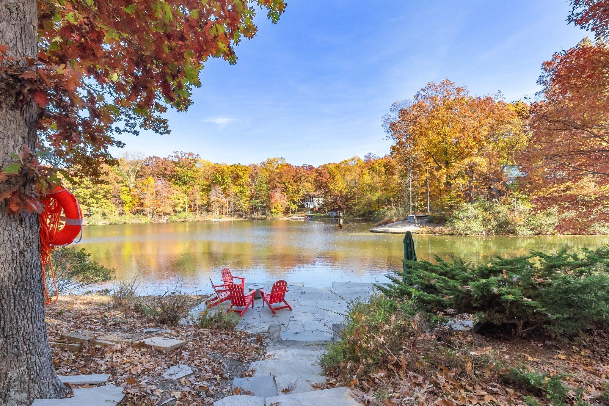 A serene lakeside setting with a clear view of the lake, surrounded by autumn foliage.