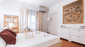 Una habitación de hotel con cama, mesita de noche, armario y una obra de arte enmarcada en la pared.
