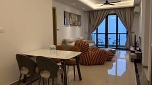 A modern living room with a dining area, a sofa, and a large window with curtains. - R&F Seine Region (Johor Bahru)